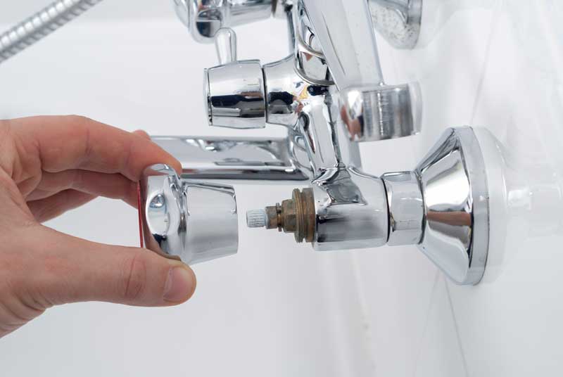 A person skillfully repairing a shower faucet, ensuring proper functionality and preventing water leakage.
