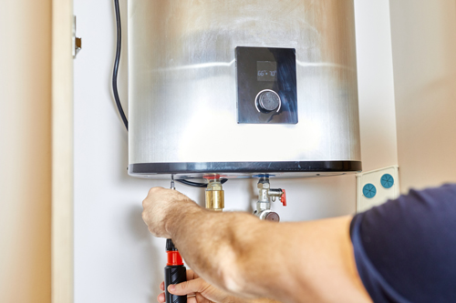 A man skillfully repairing a water heater with focused concentration and necessary tools.